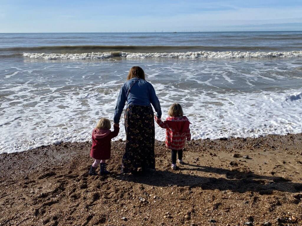 Suzanne holding the children's hands as the all look at the sea